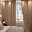 Rideau phonique beige sur mesure Cotton Silence dans une chambre, posé sur rail devant une fenêtre